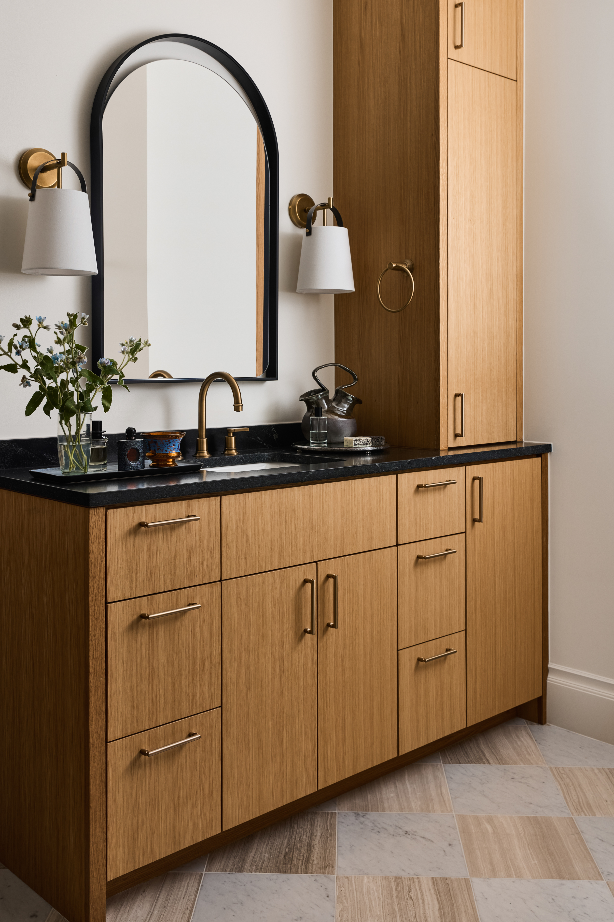 White oak vanity with black stone top and arched mirror